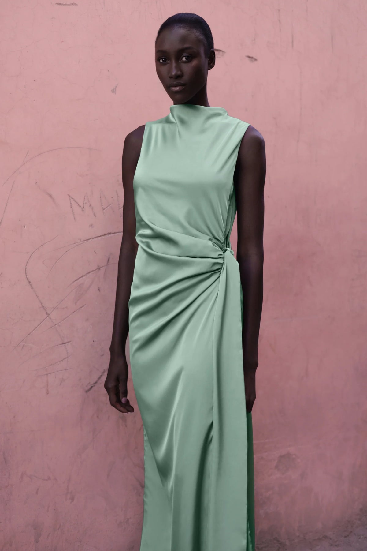 Model wearing the Baobab Vitto Maxi Dress in Jade color posing in front of a pink wall.