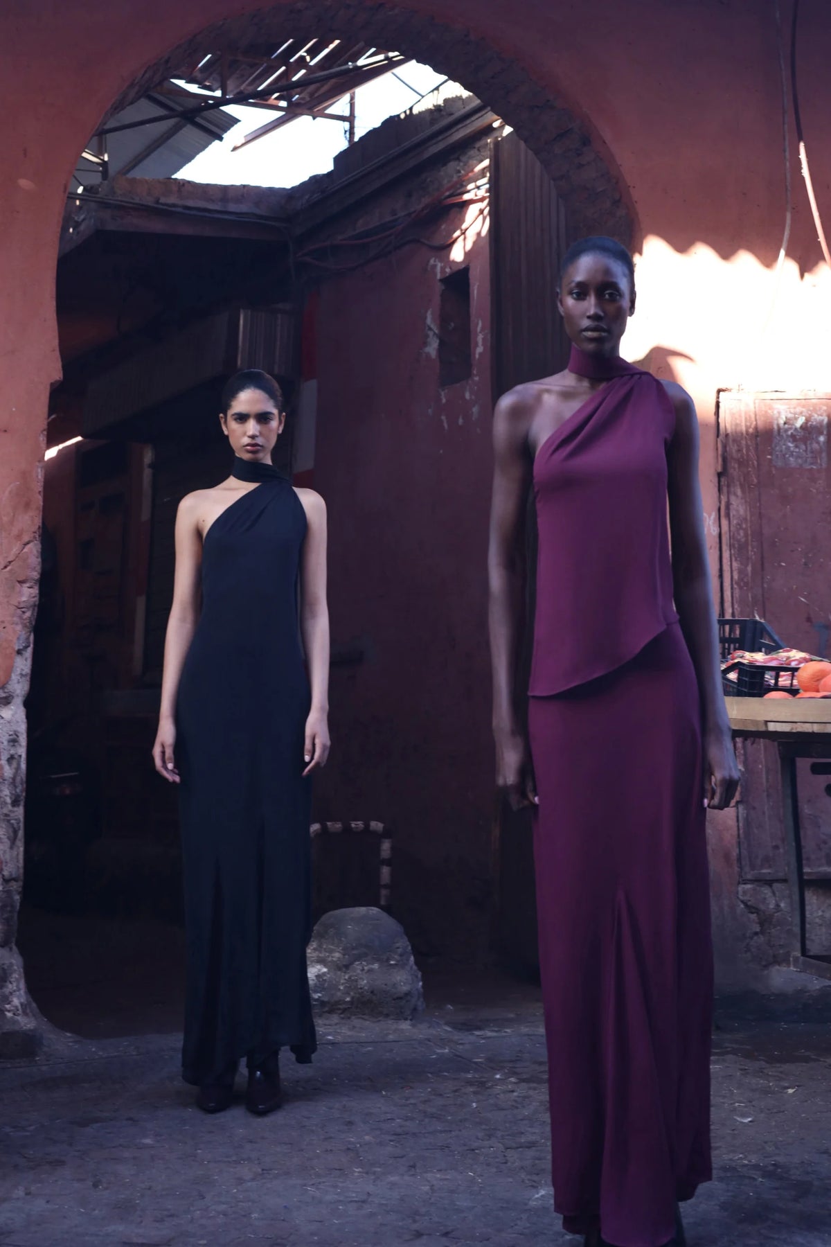 Detail of the Ari Skirt in burgundy, Textured fabric and asymmetrical neckline in architectural setting.