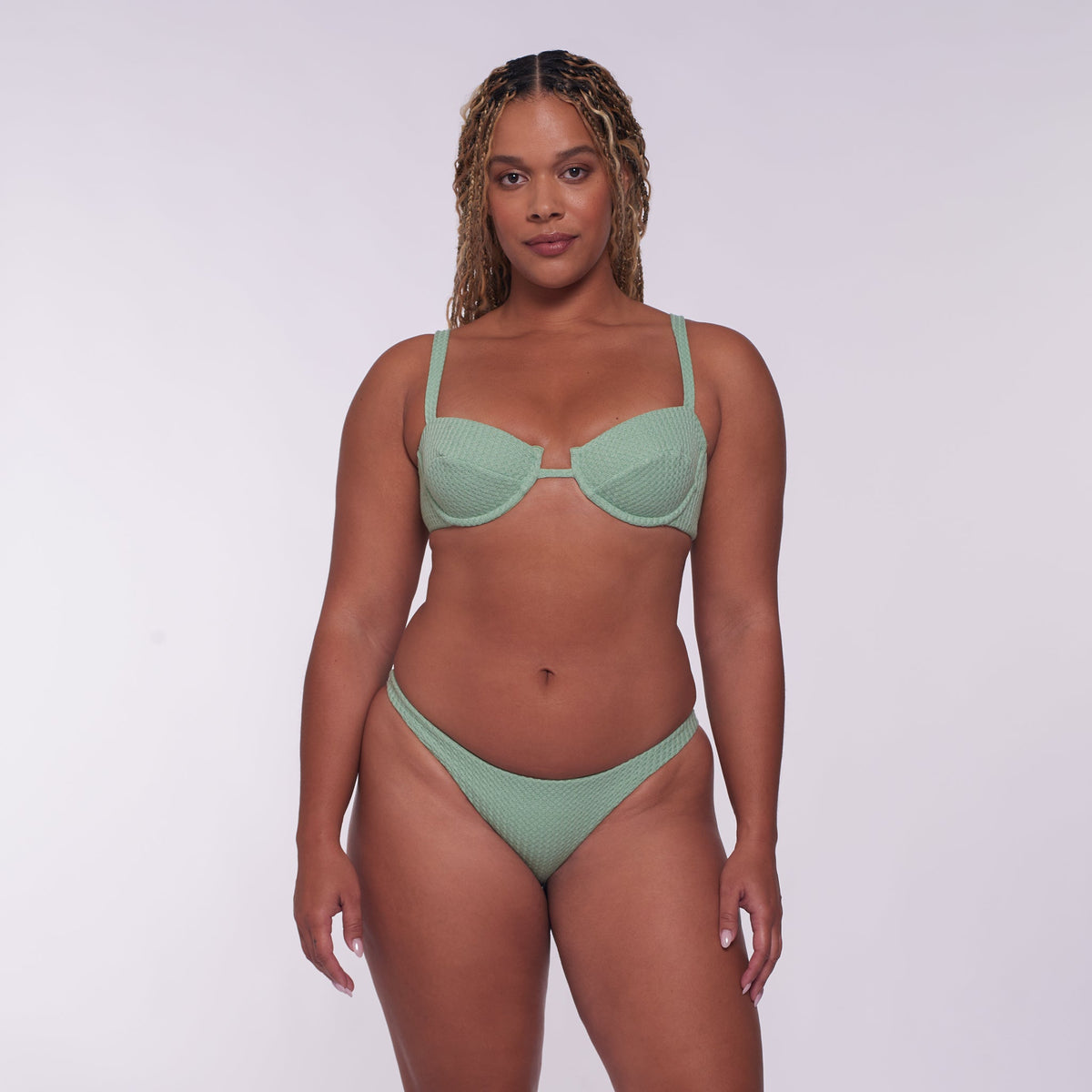 Woman wearing a green bikini set against a white background
