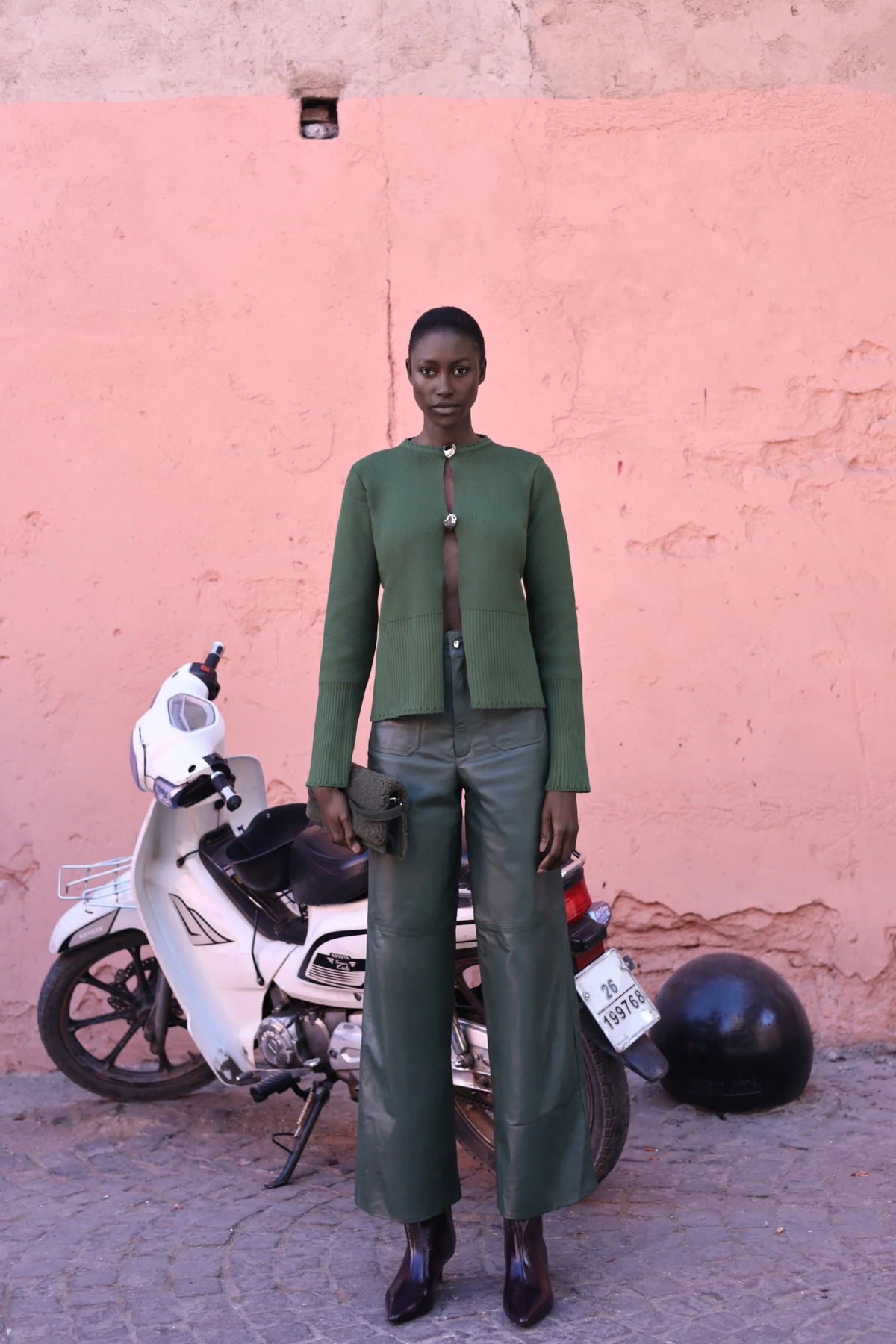 Sage green Meraky Sweater in outdoor setting, Decorative cutouts and Baobab hardware.