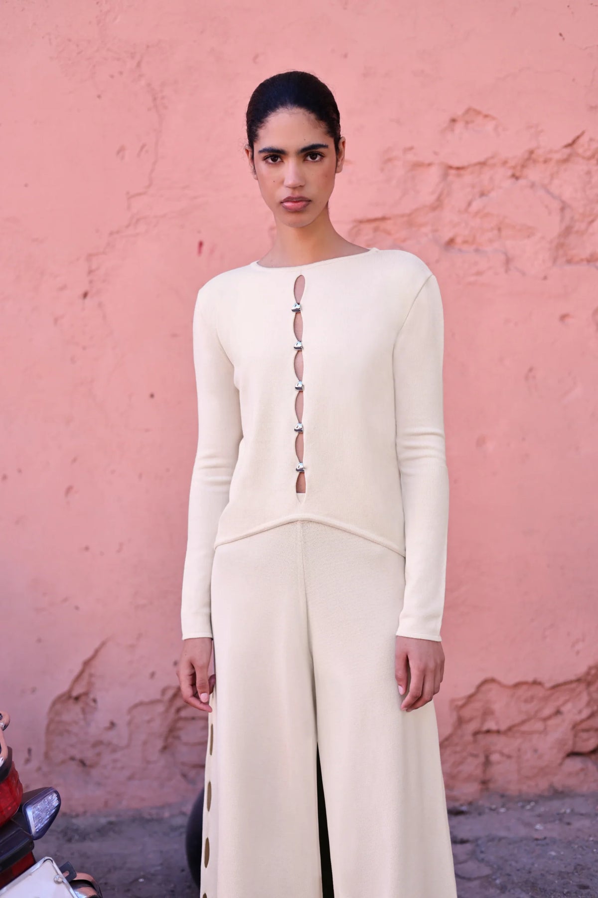 White cream Kyoto Top in urban outdoor setting, Decorative cutouts and relaxed silhouette.