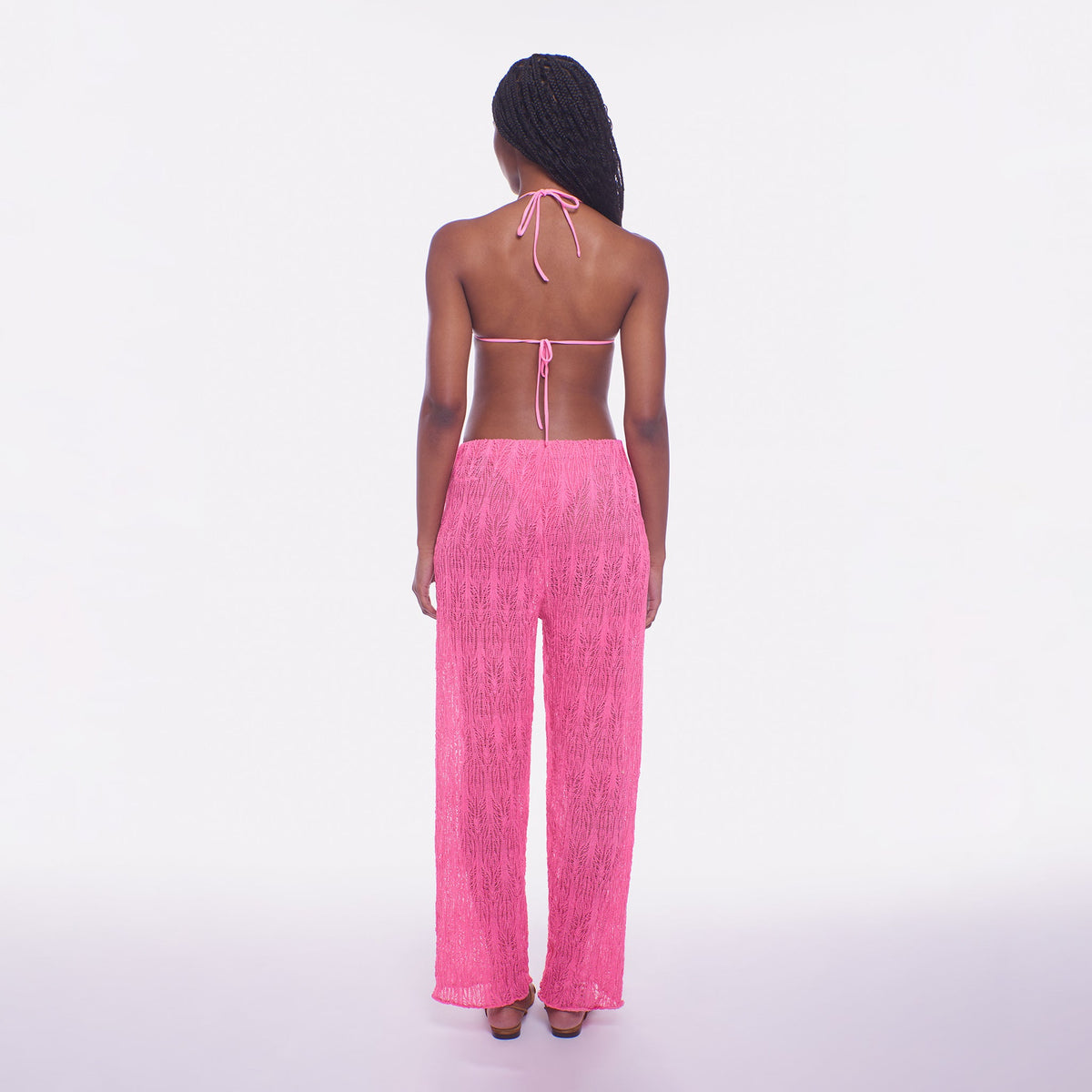 Woman wearing a pink strapless top and pants on a white background