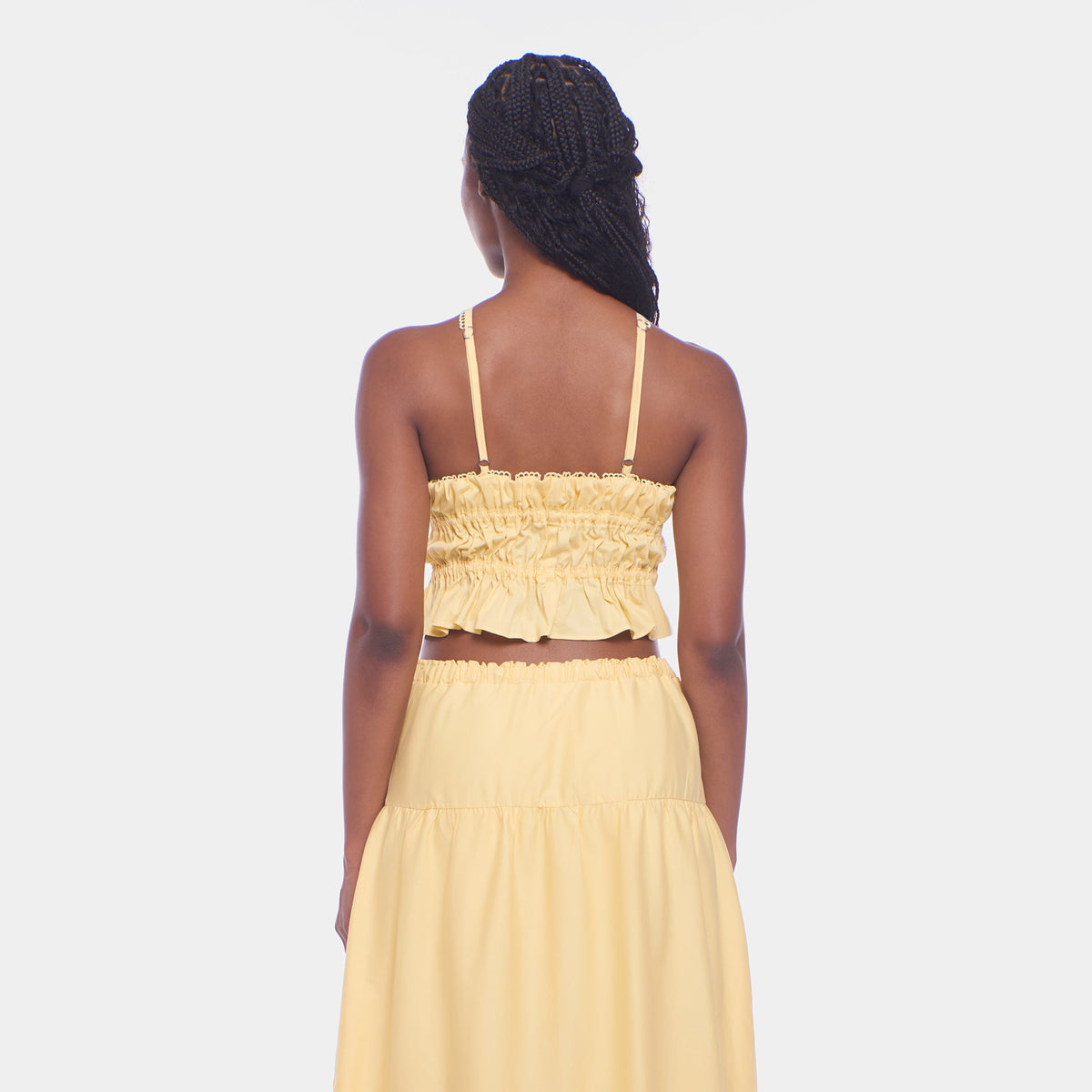 Woman wearing a yellow two-piece outfit on a white background