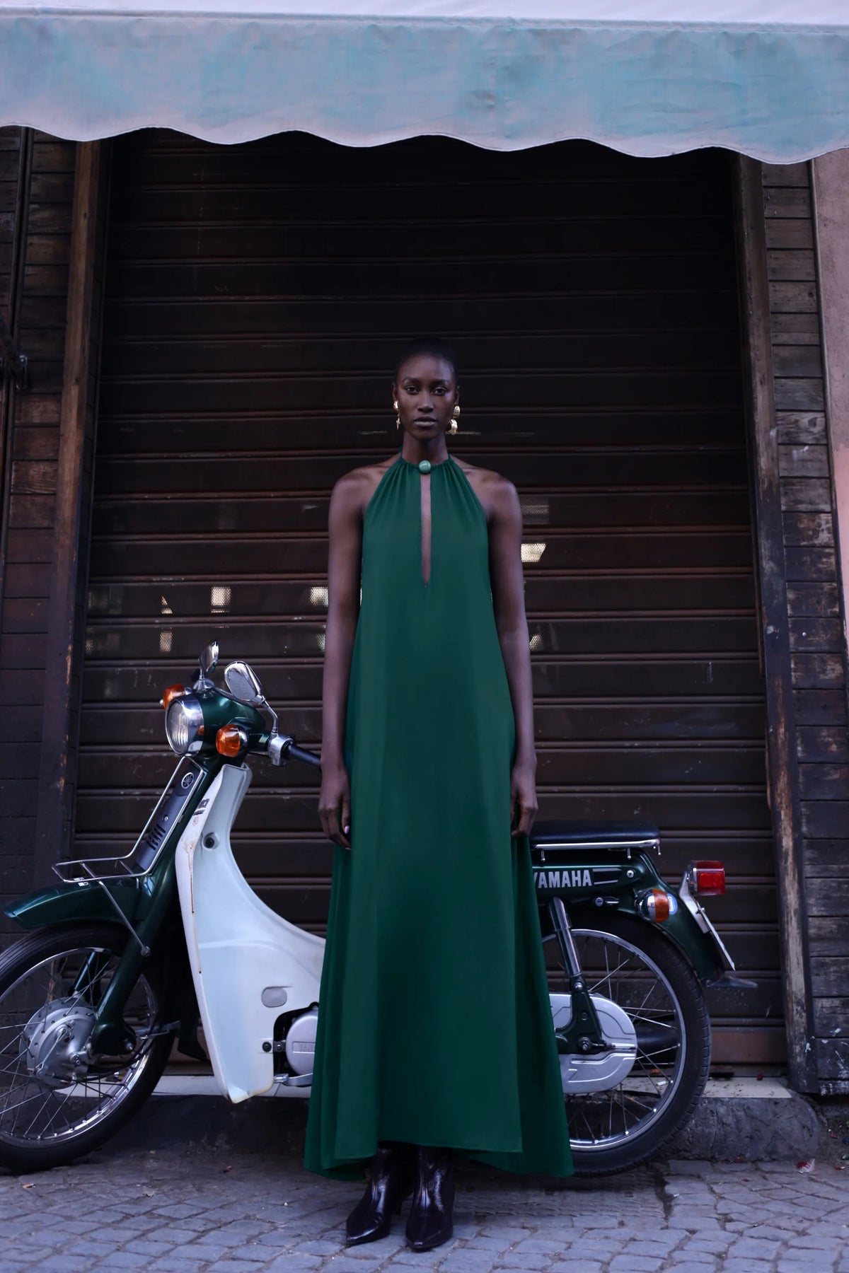 Detail of the Rondine Dress by Baobab, Glossy fabric and Front cutouts in emerald green color.