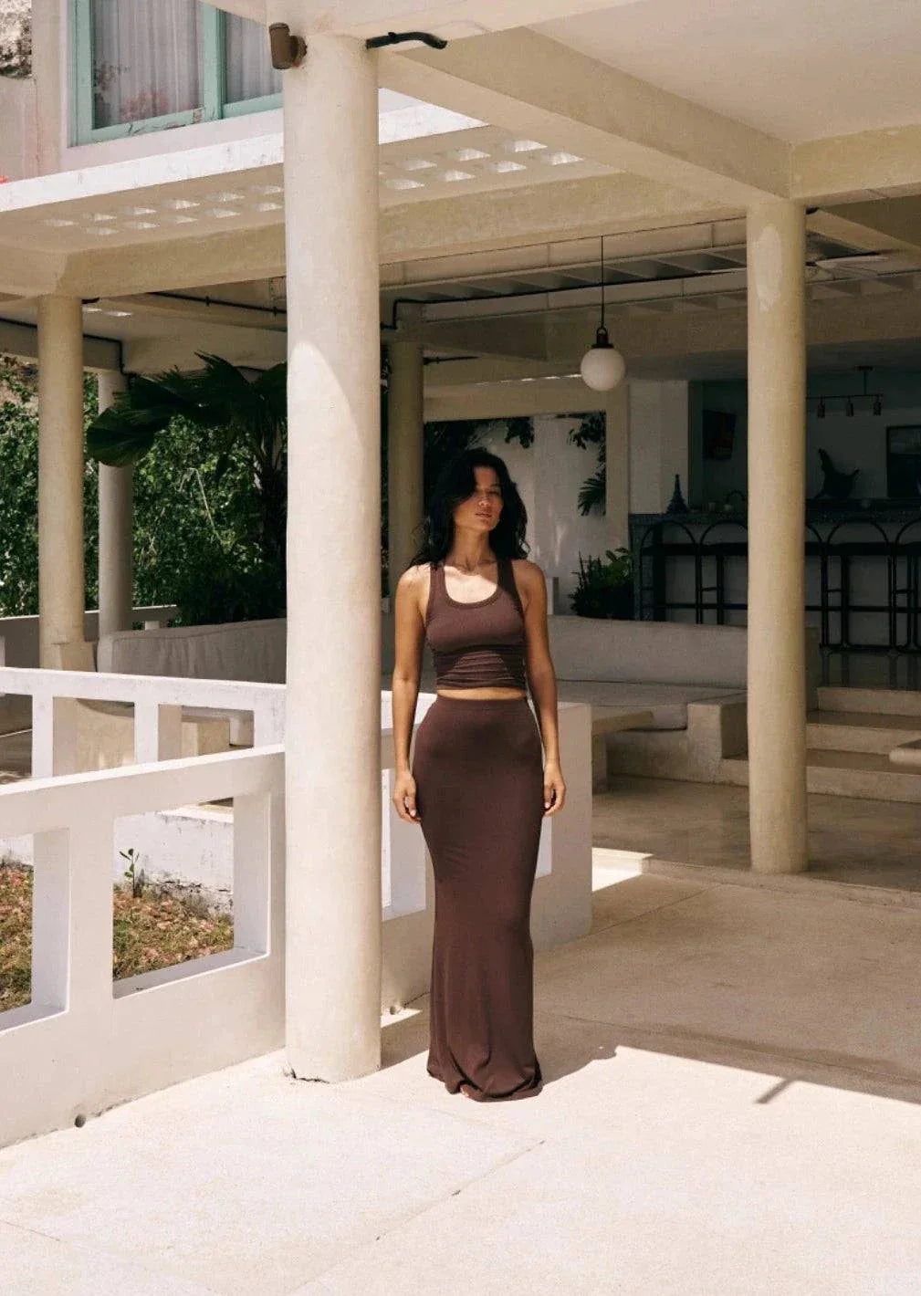 Riot Lounge Dom Maxi Skirt in chocolate color, flowing fabric, high waist design, styled with a relaxed fit and elegant silhouette.