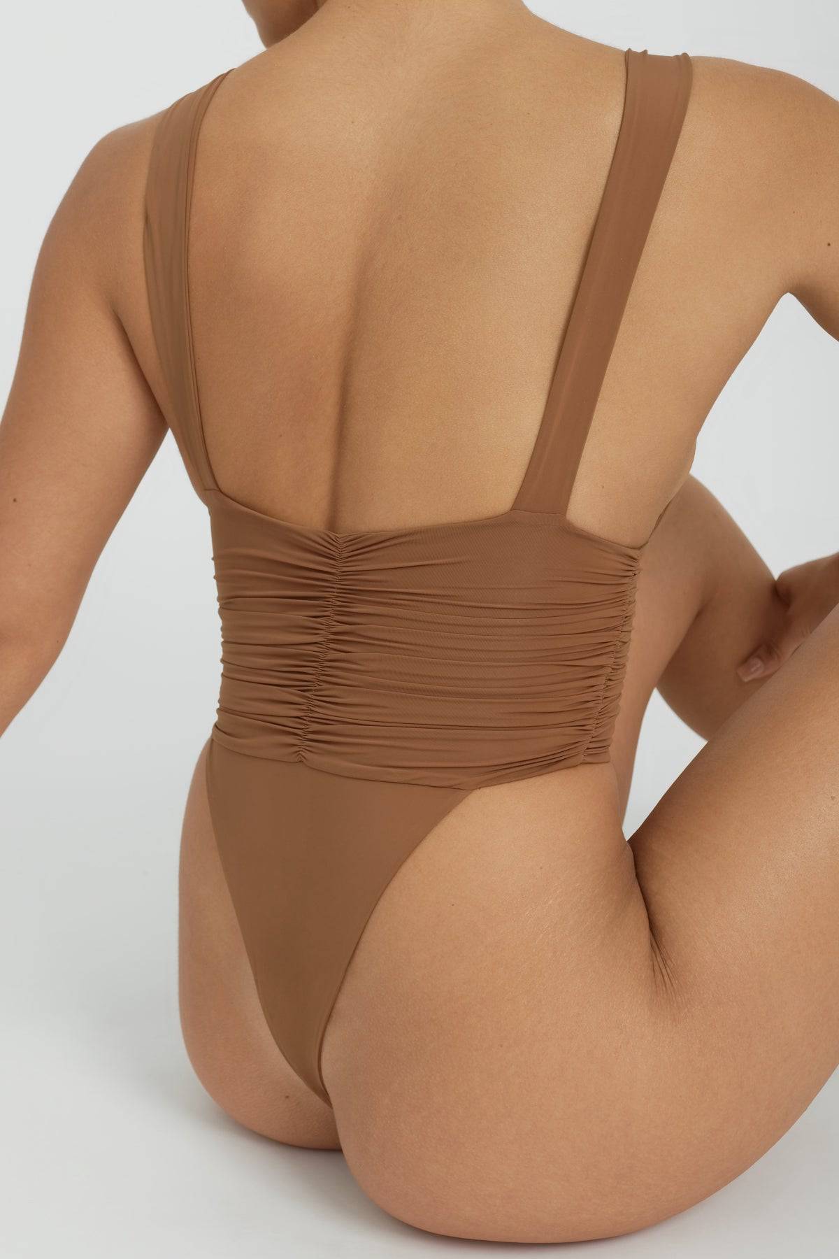 RIOT SWIM Echo One Piece Minimal swimsuit in Brown Sugar, featuring a sleek design and minimal coverage, laid flat on a white background.