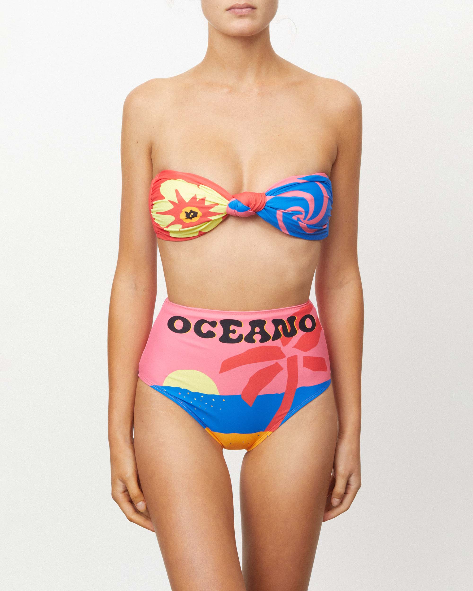 Studio image of model wearing the High Waist Pant in Oceano, highlighting its high-waisted fit and "Oceano" print.  