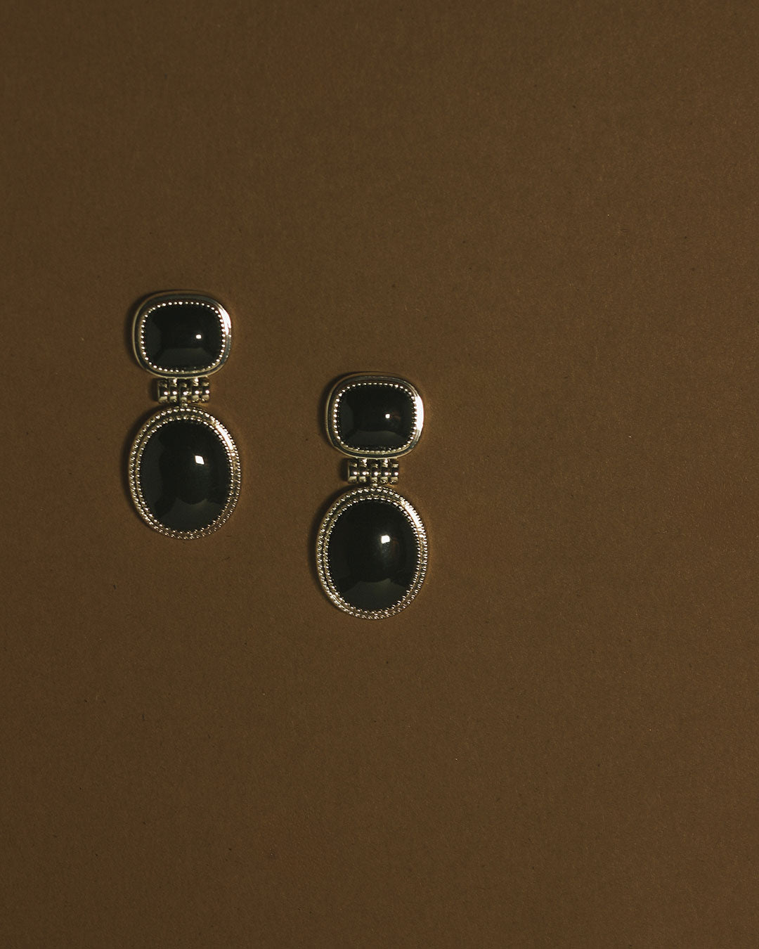 The Luv Aj Midnight Mesa Drop Studs in Gold on Brown Background