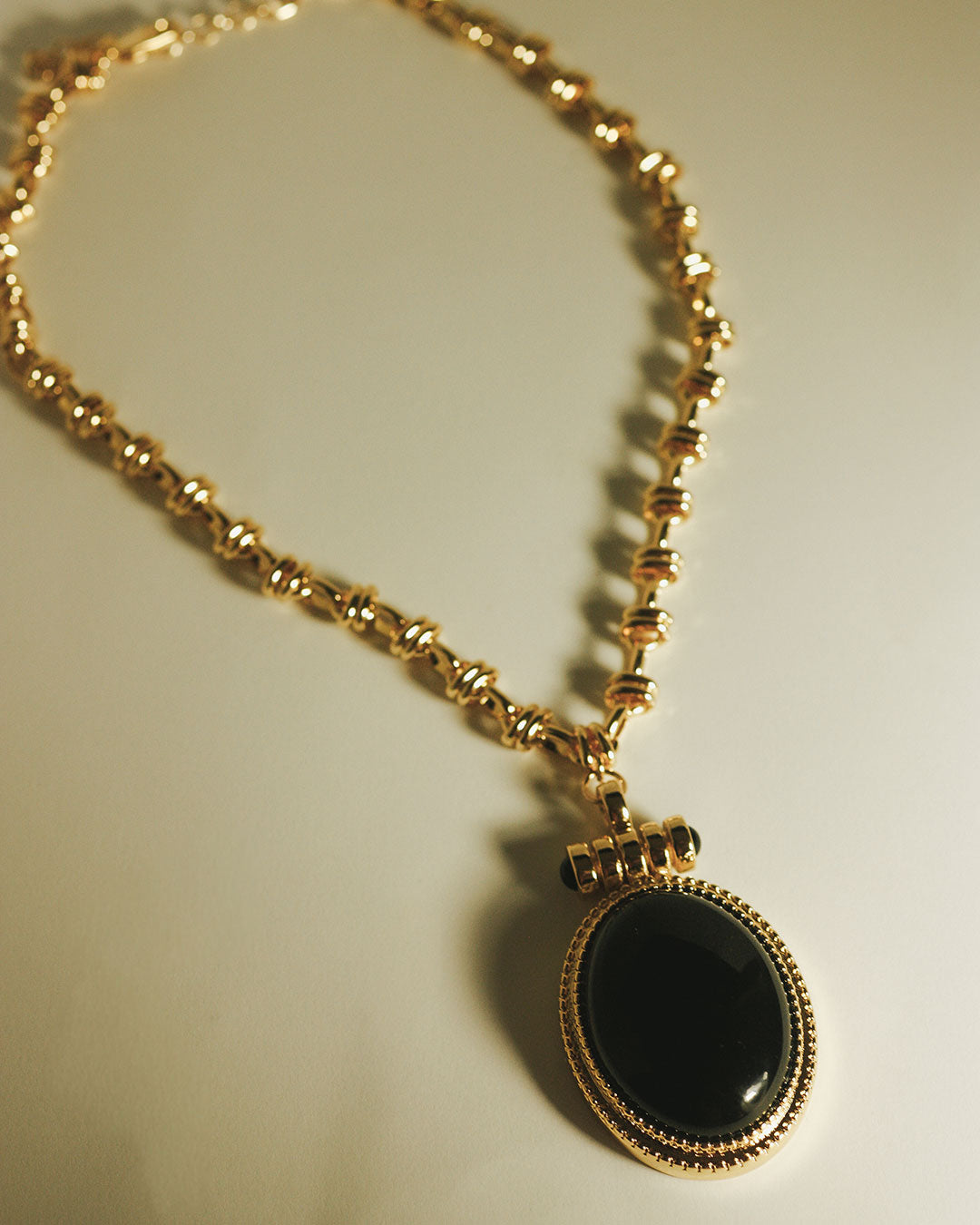 The Luv Aj Midnight Mesa Pendant Necklace in Gold laying flat on background