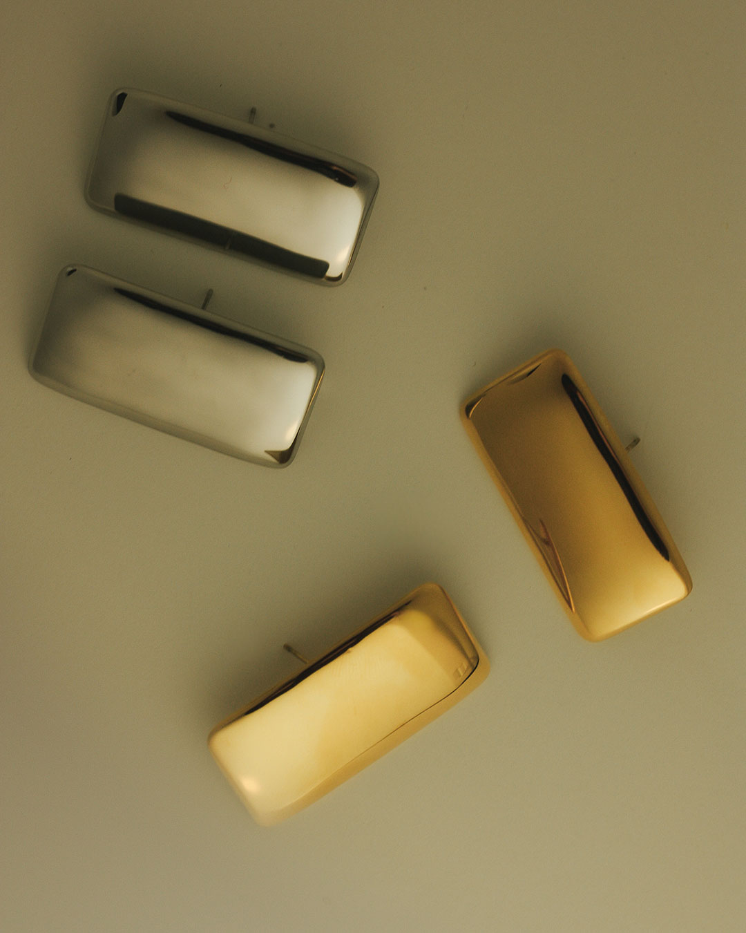 The Luv Aj Gold and Silver Solstice Metal studs, in a flat lay photo 