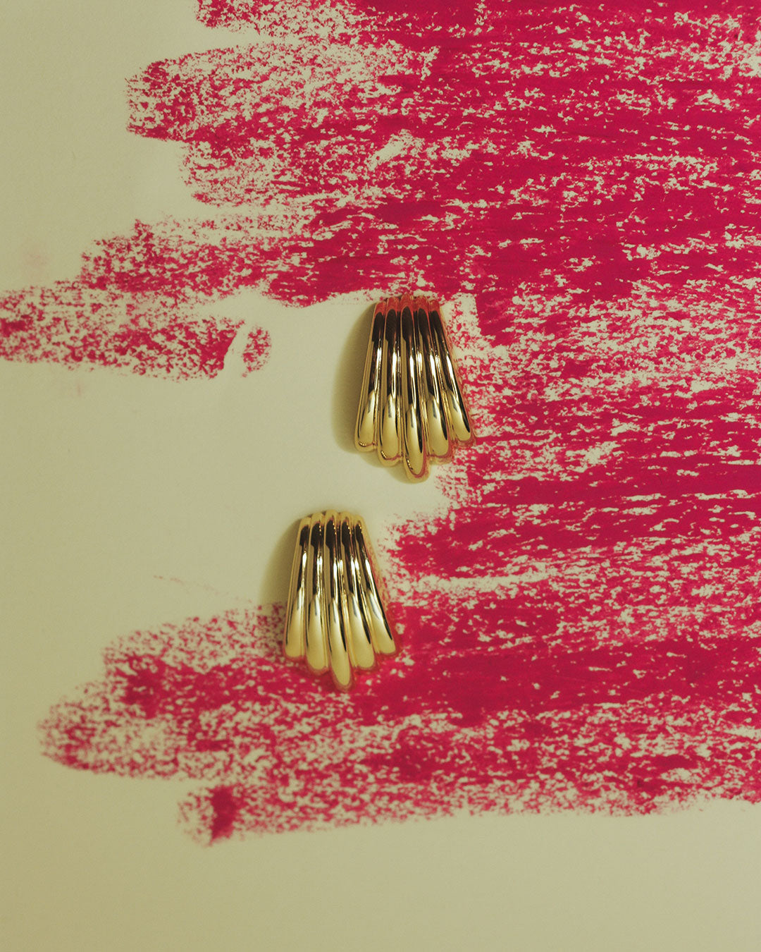The Luv Aj Sundown Statement Studs in Gold with artsy background