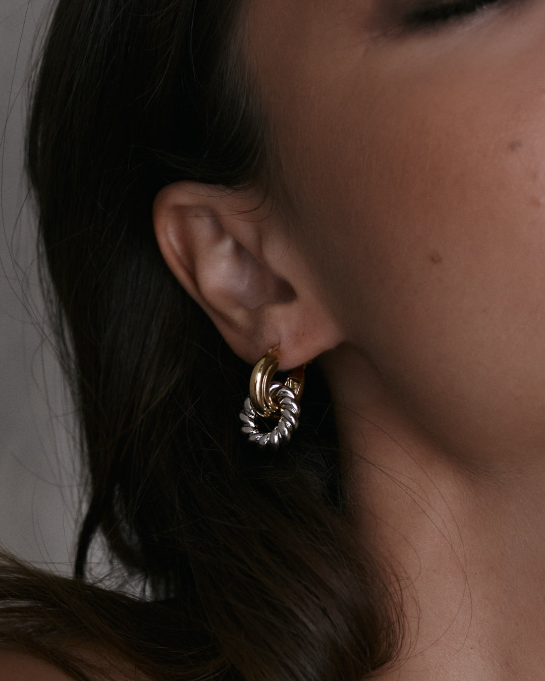 The Luv Aj Two-Tone Rope Interlock hoops in gold on model