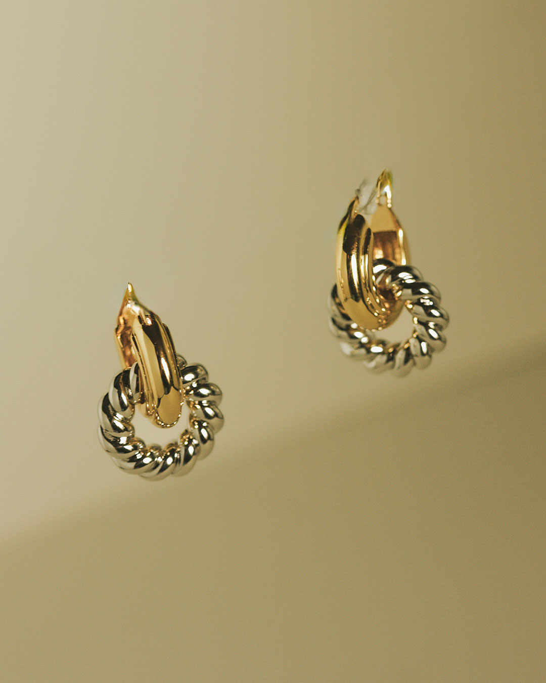 The Luv Aj Two-Tone Rope Interlock Hoops in Gold on green background
