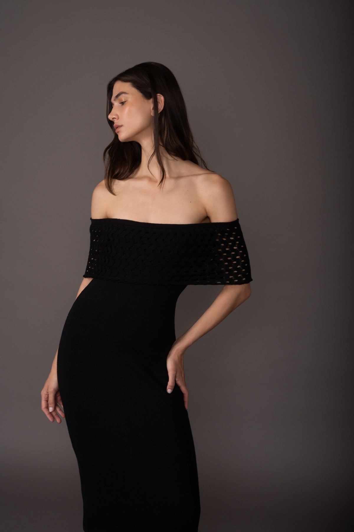 Woman wearing a black off-shoulder dress against a gray background