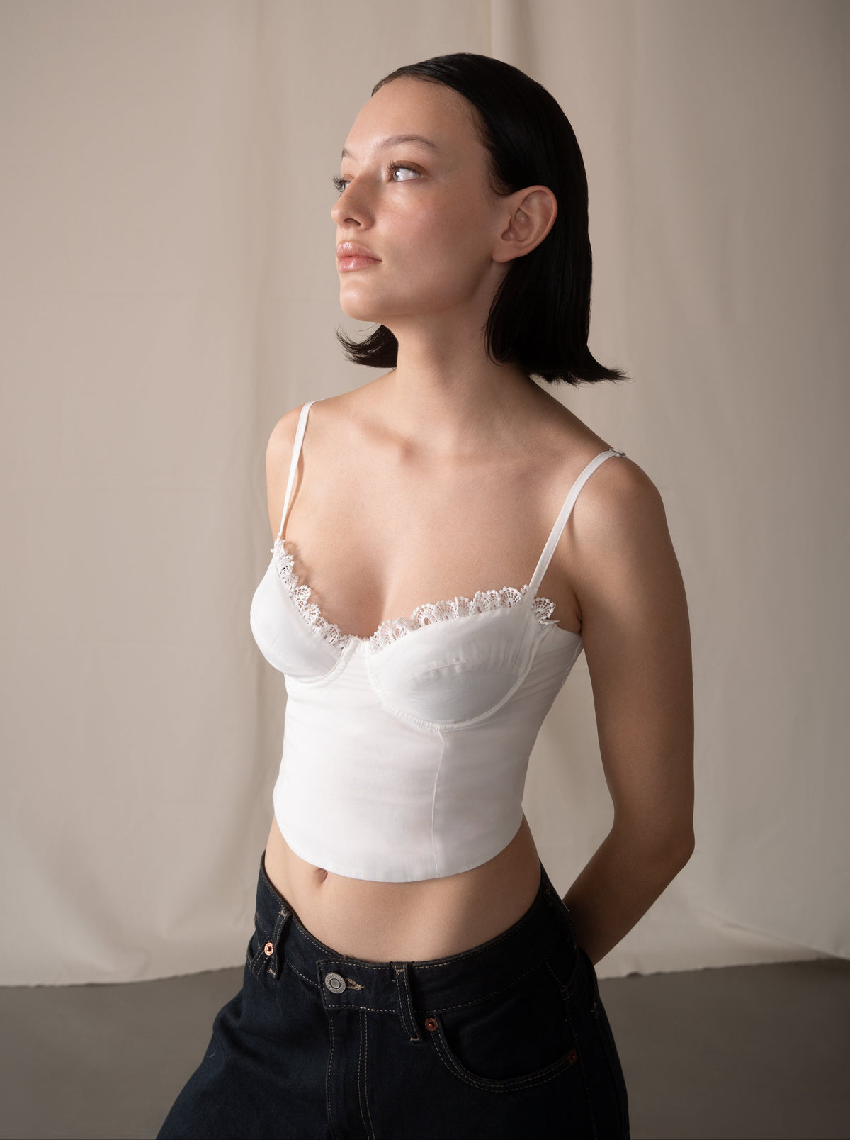 Woman wearing a white lace top against a plain background