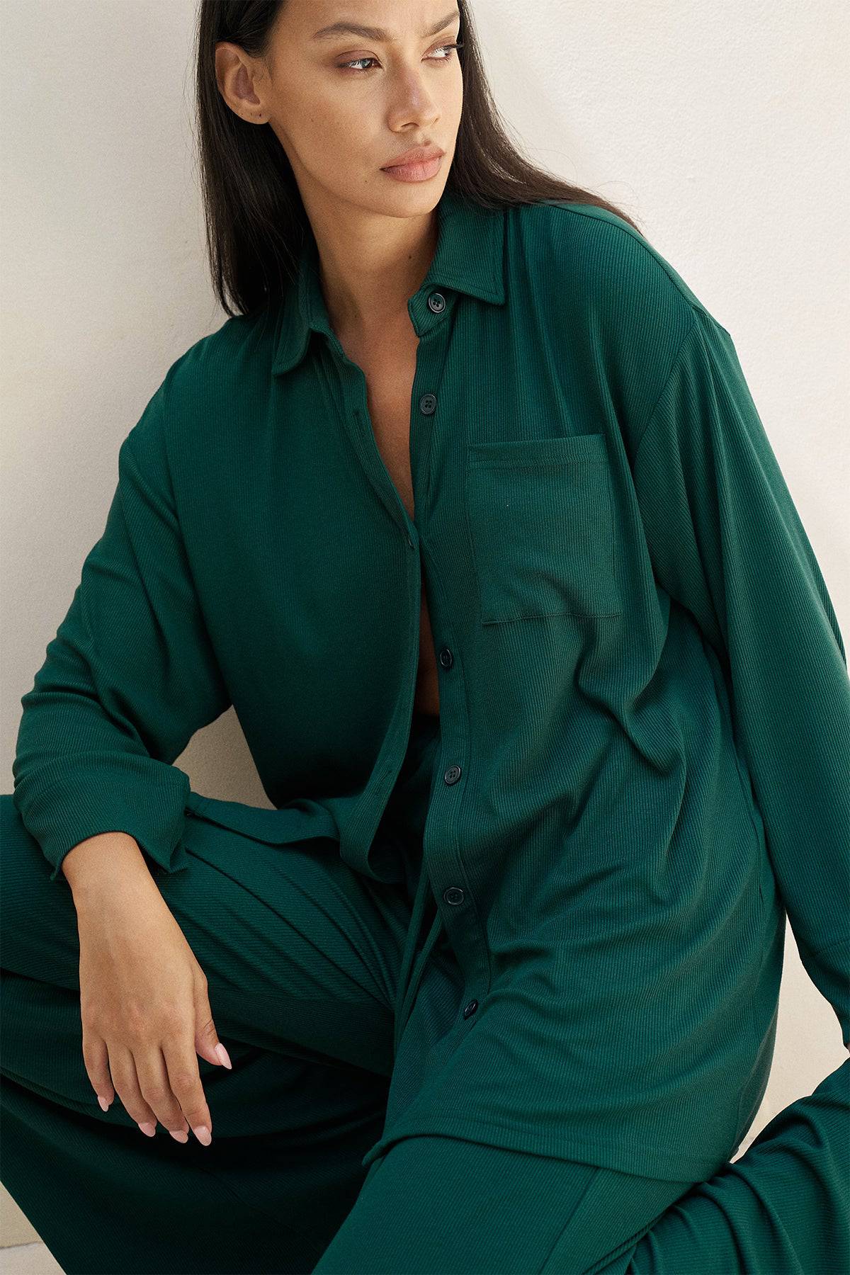 Riot Lounge Camden Button Down in Forest Green, soft ribbed casual top with a relaxed fit and classic collar, displayed on a hanger.
